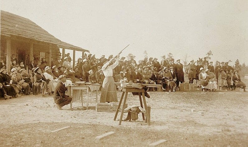 Annie Oakley takes a shot in front of a crowd.