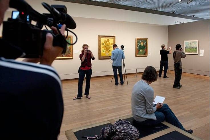 Museum goers take photos of paintings. 